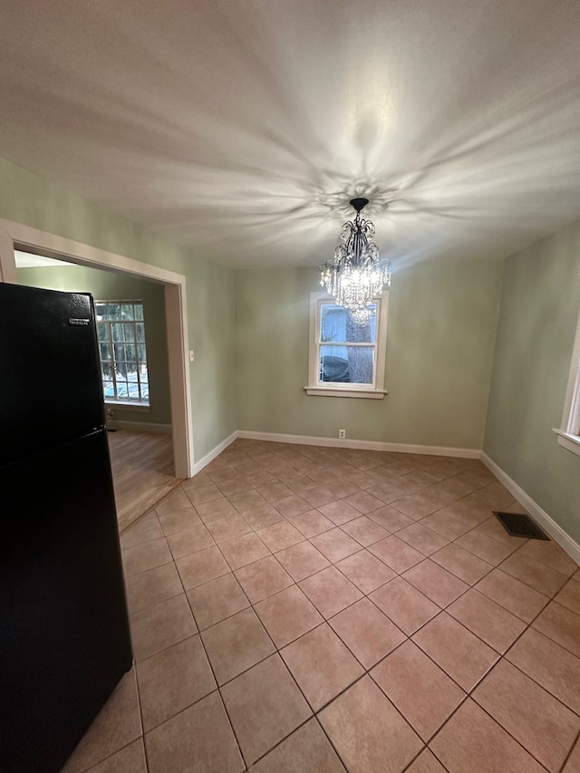 unfurnished dining area featuring baseboards, visible vents, a notable chandelier, and light tile patterned floors