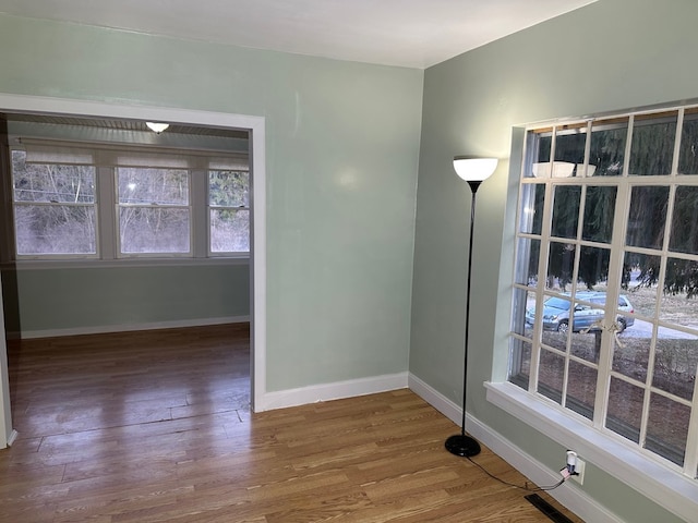 unfurnished room with wood finished floors, visible vents, and baseboards
