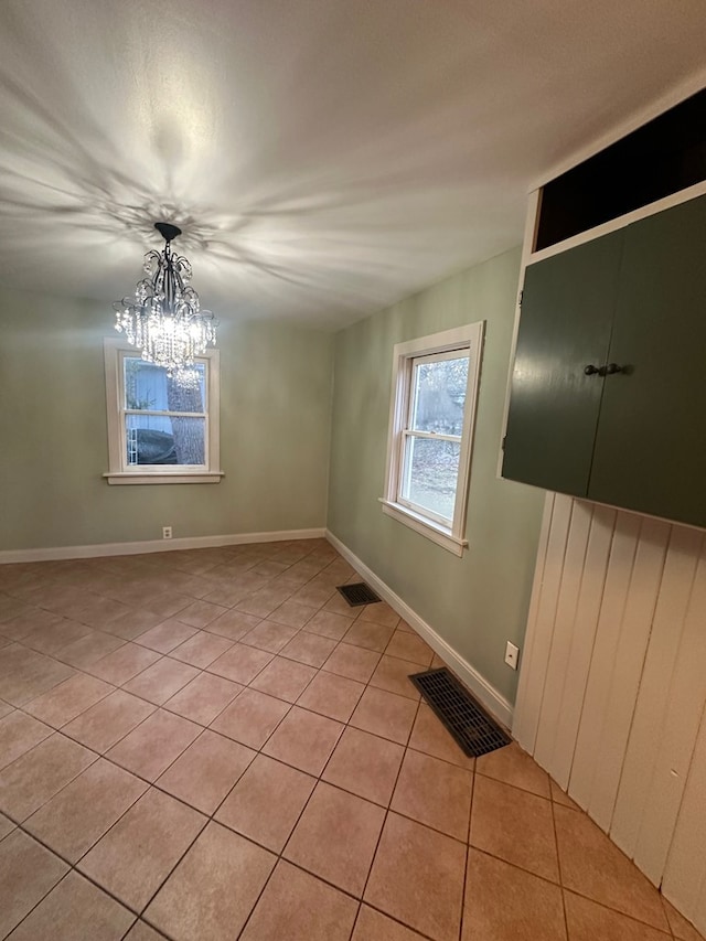 empty room featuring baseboards, visible vents, an inviting chandelier, and light tile patterned floors
