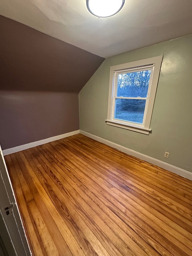 additional living space featuring vaulted ceiling, wood finished floors, and baseboards