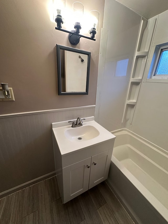 bathroom with wainscoting, shower / bathtub combination, vanity, and wood finished floors