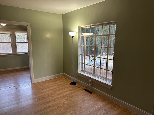 unfurnished room featuring visible vents, baseboards, and wood finished floors