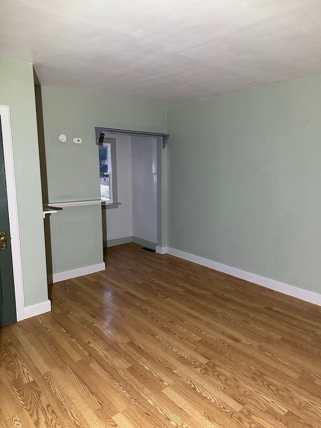 unfurnished room with baseboards and wood finished floors