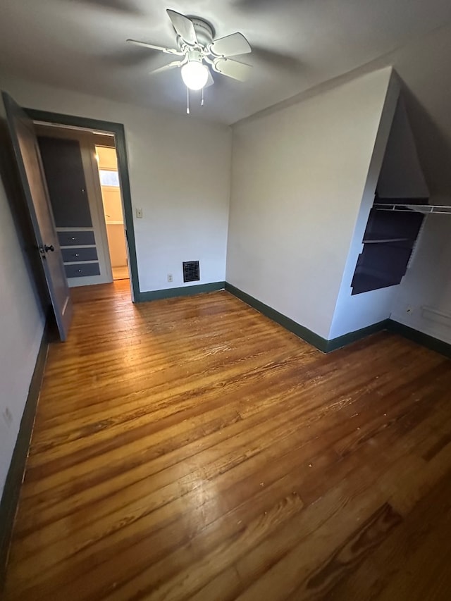 unfurnished bedroom with wood finished floors, visible vents, a ceiling fan, and baseboards