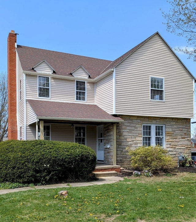 view of front of home with a chimney, a porch, a front lawn, and stone siding