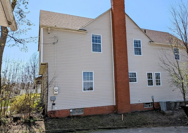 back of house with roof with shingles, central AC, and a chimney