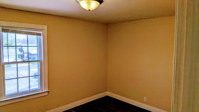 unfurnished room with dark wood-type flooring and baseboards