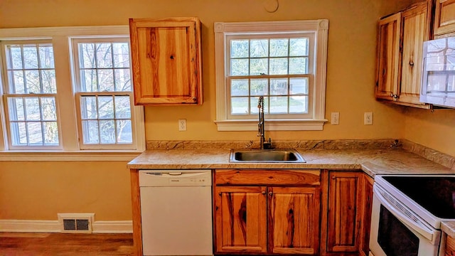kitchen with a wealth of natural light, visible vents, white appliances, and a sink