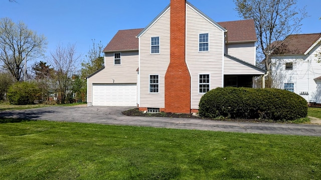 view of home's exterior featuring a chimney, a garage, driveway, roof with shingles, and a lawn