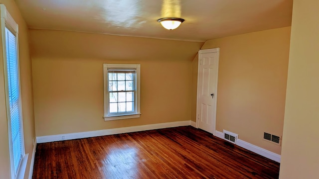 empty room featuring visible vents, dark wood-style flooring, and baseboards