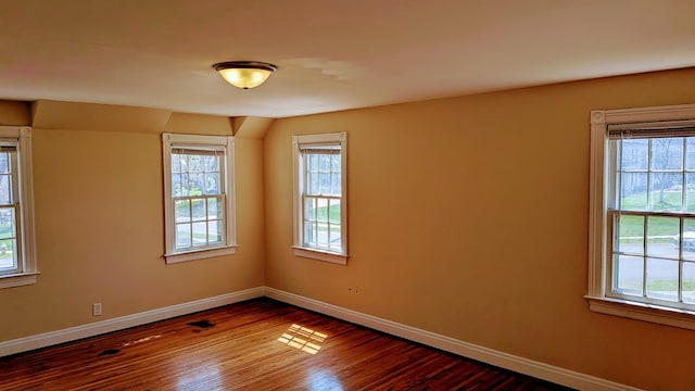 empty room with baseboards, dark wood-type flooring, and plenty of natural light