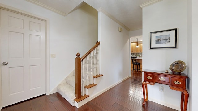 stairs with hardwood / wood-style flooring and ornamental molding