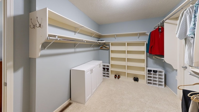 spacious closet featuring light colored carpet