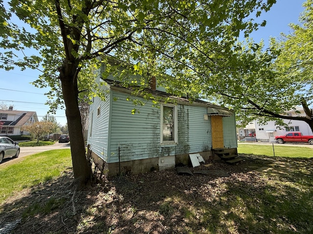 view of side of property with fence, a chimney, and entry steps