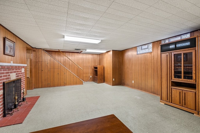 basement with carpet flooring, wood walls, and a fireplace