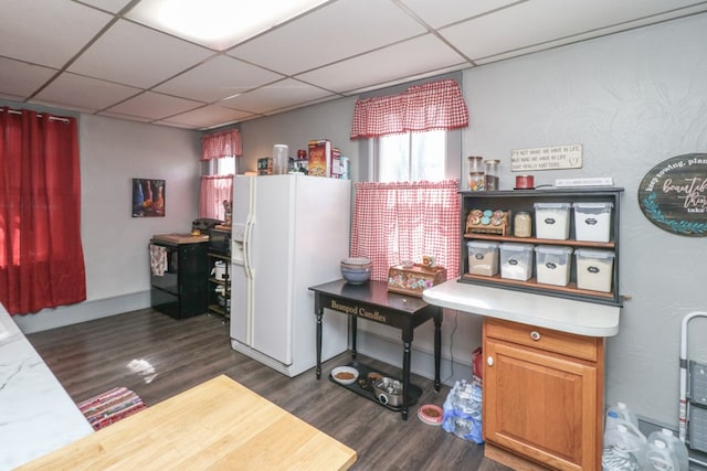 interior space with white refrigerator with ice dispenser, dark wood-type flooring, and a paneled ceiling
