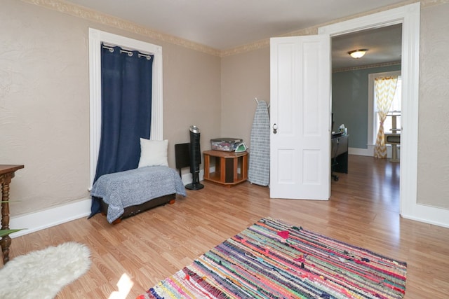 sitting room with light wood-style flooring, ornamental molding, and baseboards