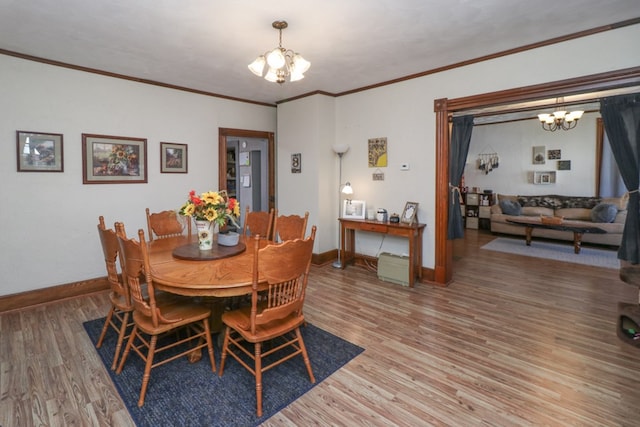 dining space featuring baseboards, crown molding, light wood-style flooring, and a chandelier
