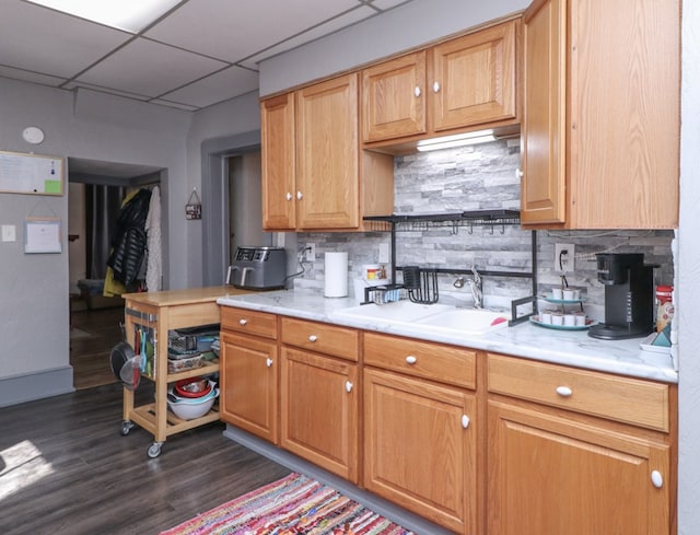 kitchen with dark wood-style flooring, light countertops, a sink, and tasteful backsplash