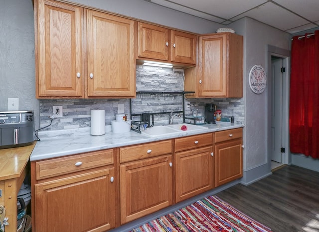 kitchen with backsplash, light countertops, a sink, and dark wood finished floors
