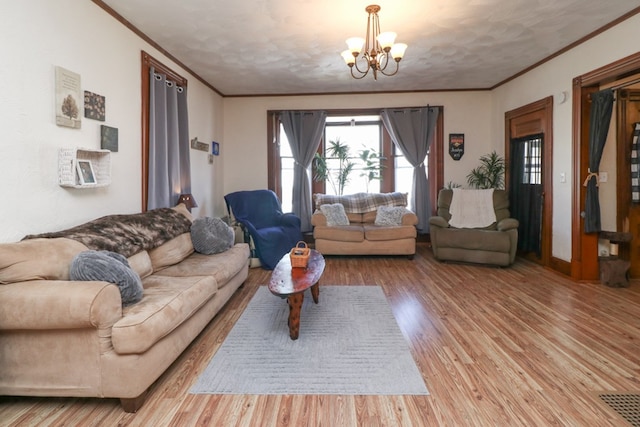 living room with crown molding, light wood-style flooring, and an inviting chandelier