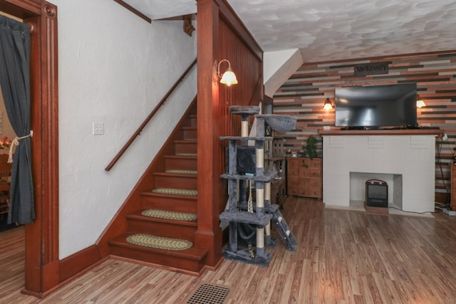 staircase with baseboards, a fireplace with flush hearth, and wood finished floors