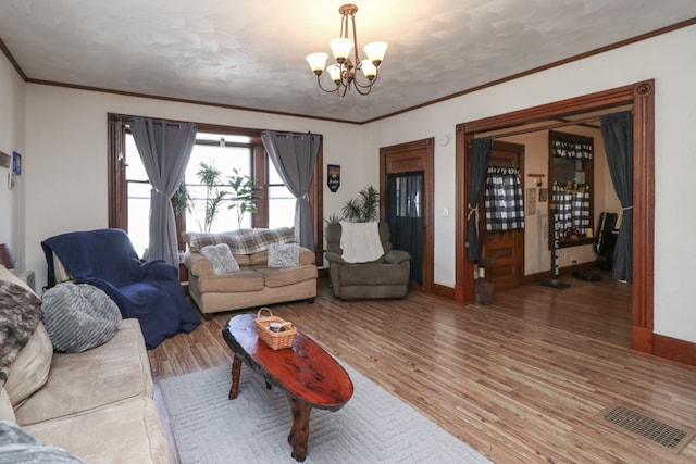 living room featuring a notable chandelier, wood finished floors, baseboards, visible vents, and ornamental molding