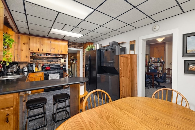 kitchen featuring kitchen peninsula, a paneled ceiling, sink, black appliances, and separate washer and dryer