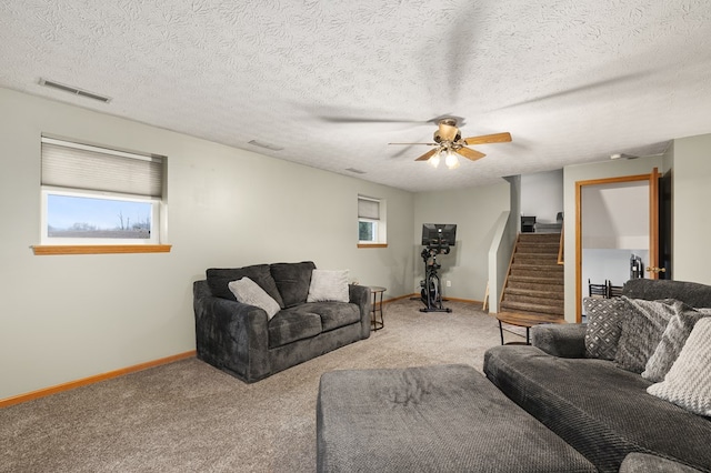 carpeted living room with ceiling fan and a textured ceiling