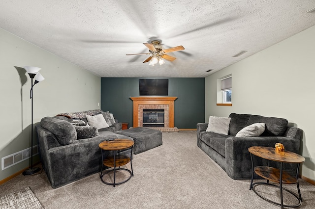 living room with a textured ceiling, carpet floors, a brick fireplace, and ceiling fan