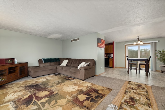 carpeted living room featuring a chandelier and a textured ceiling