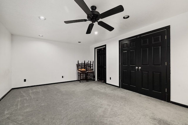 unfurnished bedroom with ceiling fan, light carpet, and multiple closets