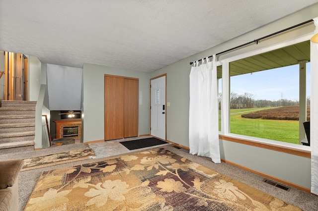 carpeted entryway with a textured ceiling