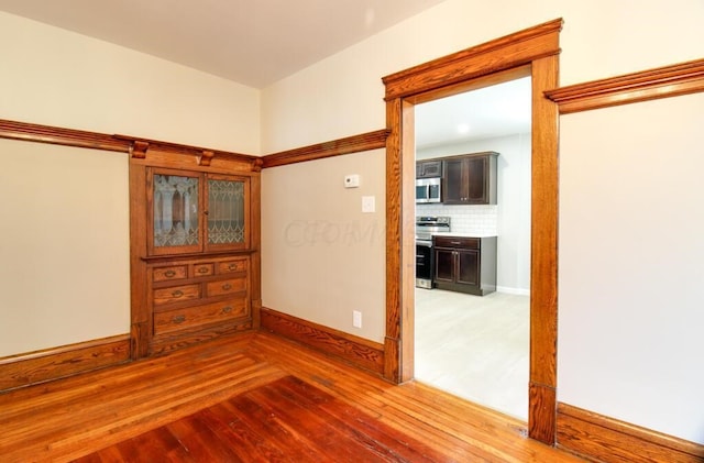 unfurnished room with baseboards and hardwood / wood-style floors