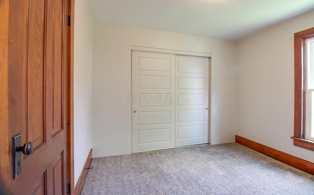 unfurnished bedroom with a closet, carpet floors, multiple windows, and baseboards