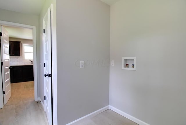 clothes washing area featuring laundry area, baseboards, and washer hookup