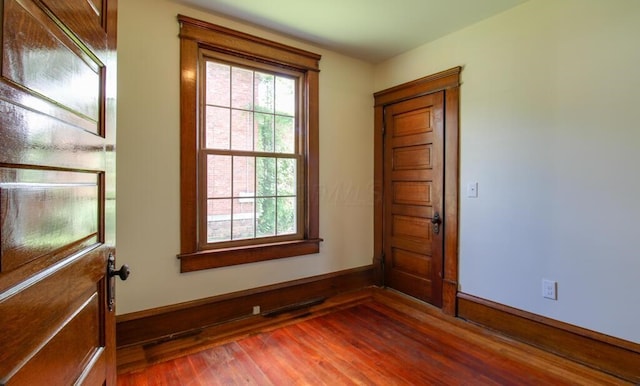 spare room with visible vents, baseboards, and wood finished floors