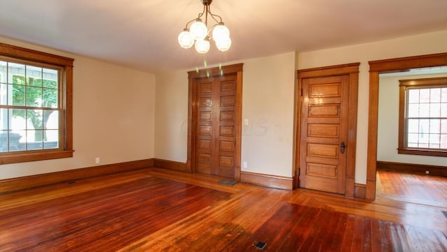 unfurnished bedroom with baseboards, a chandelier, and hardwood / wood-style flooring