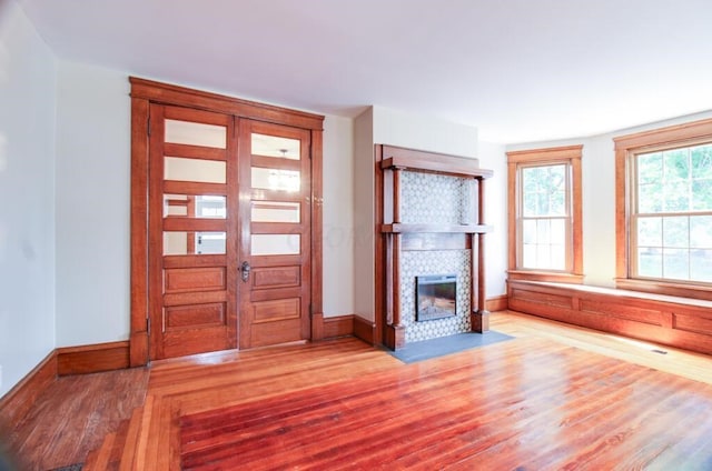 foyer entrance with a tiled fireplace, baseboards, and wood finished floors