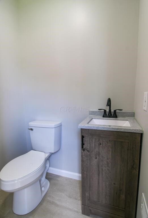 half bath with toilet, vanity, and baseboards