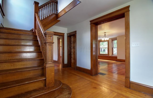 stairway featuring visible vents, baseboards, wood finished floors, and a chandelier