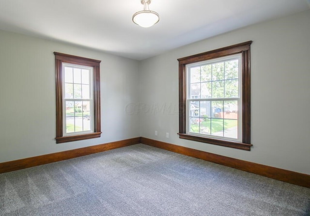 unfurnished room featuring carpet and baseboards