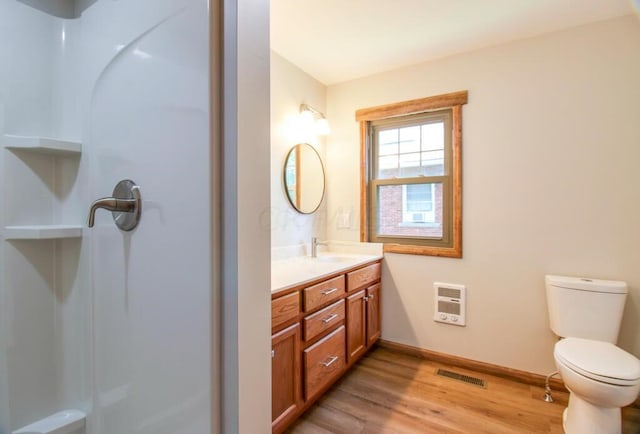 bathroom with vanity, heating unit, wood finished floors, visible vents, and toilet