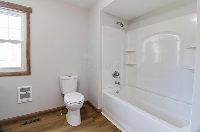 bathroom featuring visible vents, toilet, wood finished floors, baseboards, and bathtub / shower combination