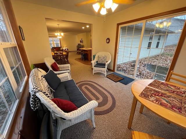 carpeted living room featuring ceiling fan with notable chandelier