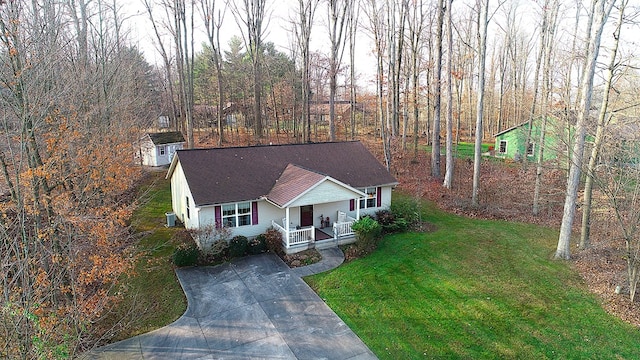 view of front of property featuring central AC unit, a storage unit, a porch, and a front yard