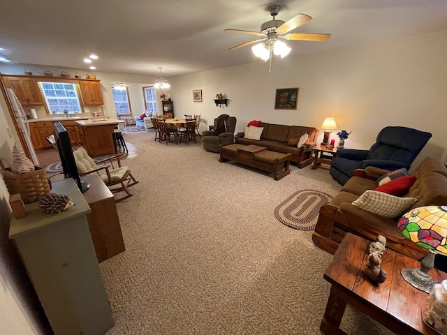 carpeted living room with ceiling fan with notable chandelier