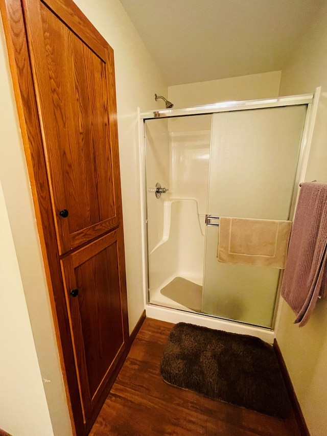 bathroom with hardwood / wood-style floors and a shower with shower door