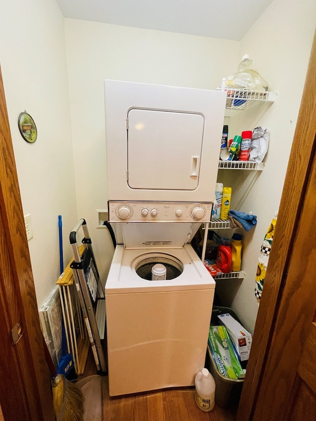 laundry room featuring hardwood / wood-style flooring and stacked washer / dryer