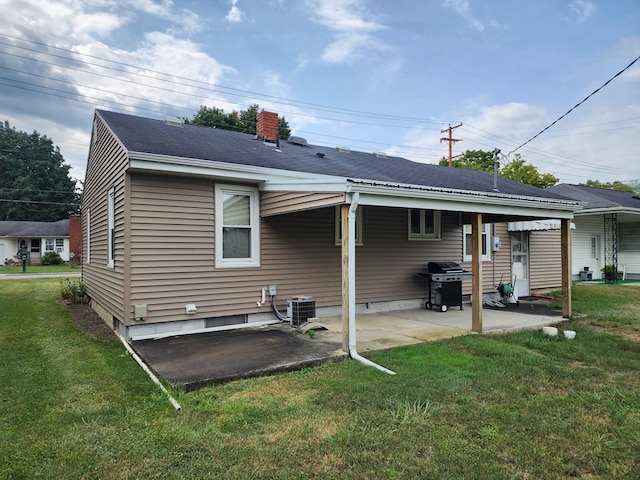 rear view of property with a lawn, a patio area, and central air condition unit